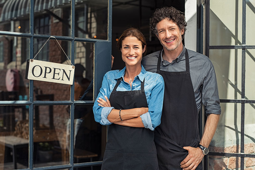 Happy business owners in front of shop