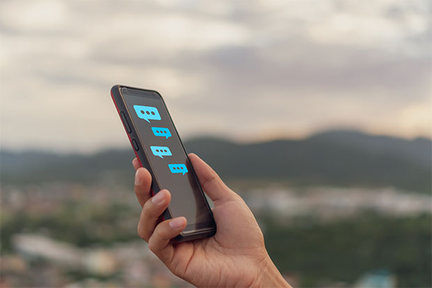 hand holding cellphone with chat bubbles